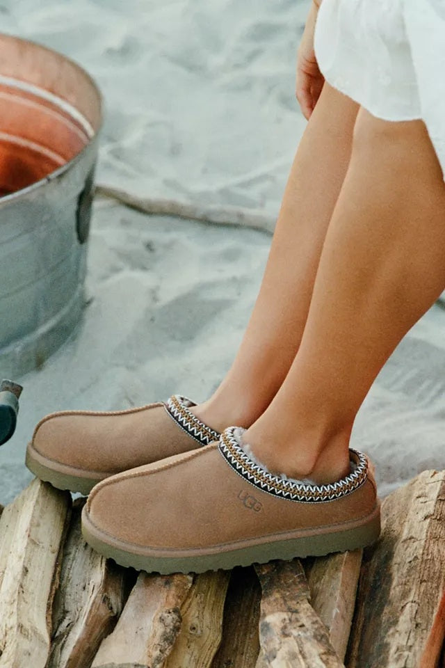 Chestnut UGG slippers worn beside the beach.